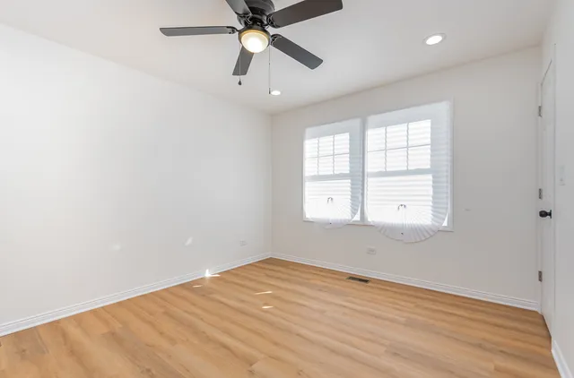 an empty room with a window and a fan