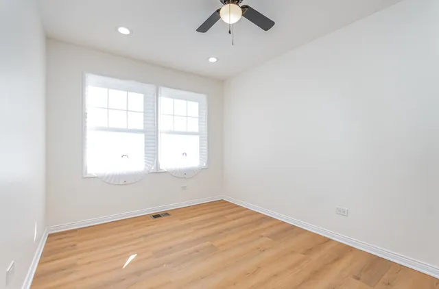 an empty room with a window and a ceiling fan