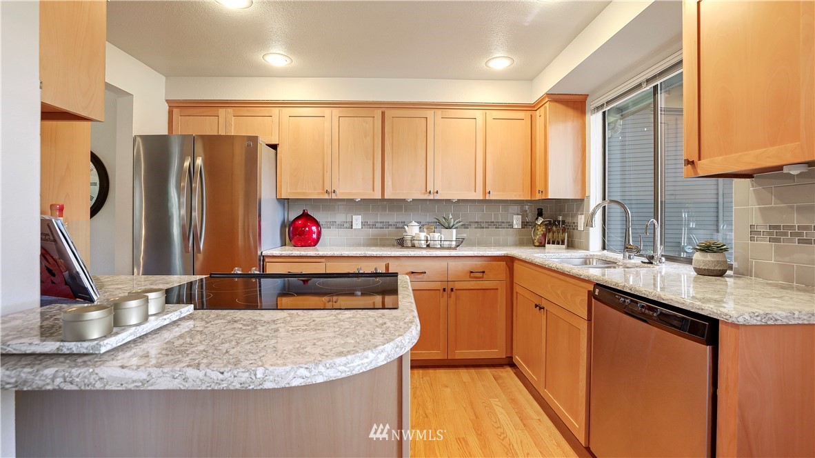 14101 148th Place Southeast Renton, WA 98059 - Photo 16 of 36 a kitchen with kitchen island granite countertop a sink a counter top space and cabinets