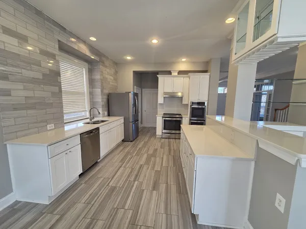 a large kitchen with stainless steel appliances kitchen island granite countertop a stove and a sink