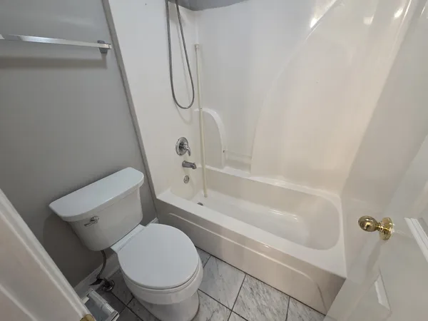 a white toilet sitting next to a bath tub