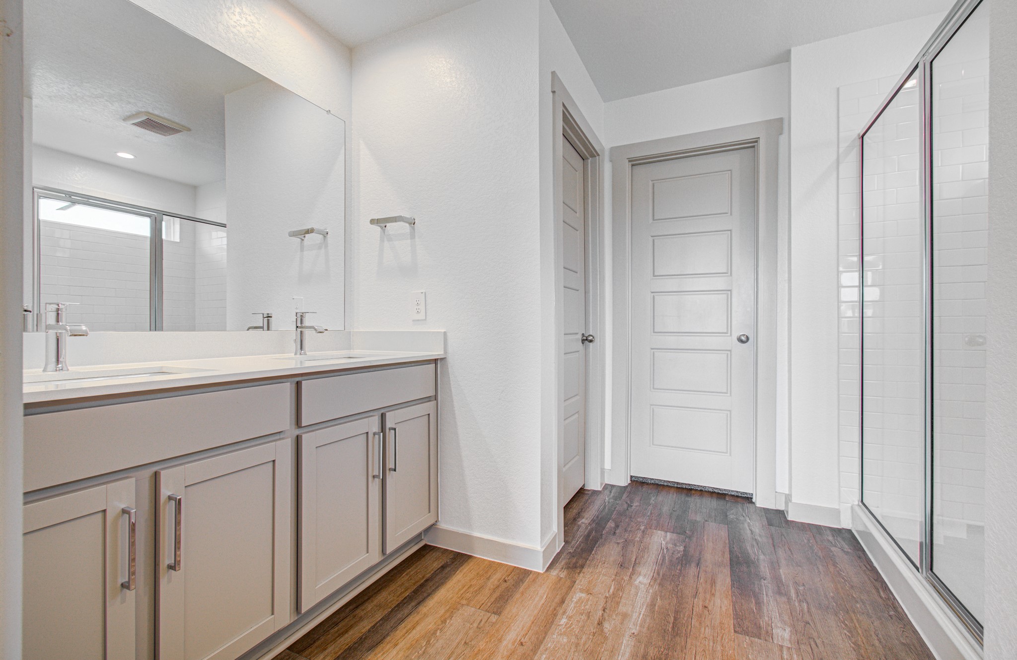 7903 Wrangler Shack Lane Rosharon, TX 77583 - Photo 26 of 29 This modern bathroom boasts a double vanity with sleek fixtures, a large mirror, a spacious glass-enclosed shower, and stylish wood-look flooring, creating a bright and inviting oasis.