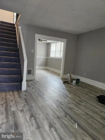 a view of an empty room with wooden floor and stairs