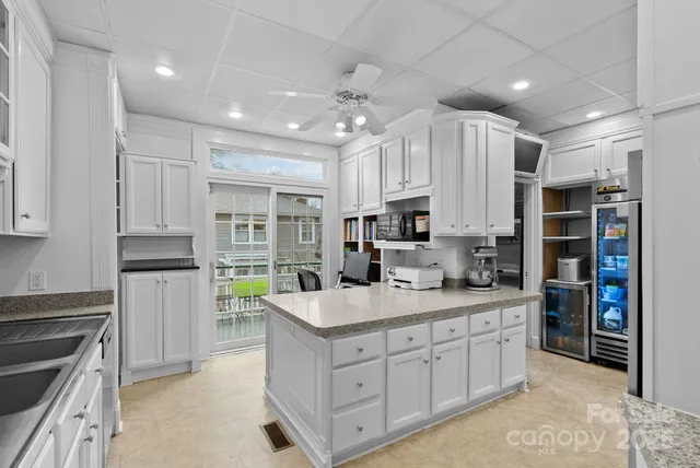 a kitchen with kitchen island granite countertop a sink cabinets and stainless steel appliances