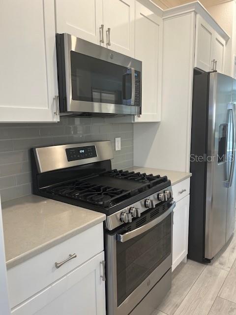 7947 Southwest 89th Loop Ocala, FL 34476 - Photo 8 of 25 a kitchen with stainless steel appliances granite countertop a stove microwave and refrigerator