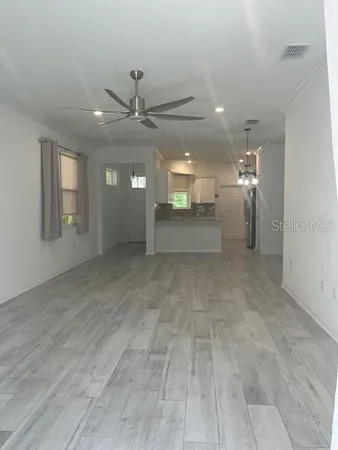 a view of an empty room with window and wooden floor