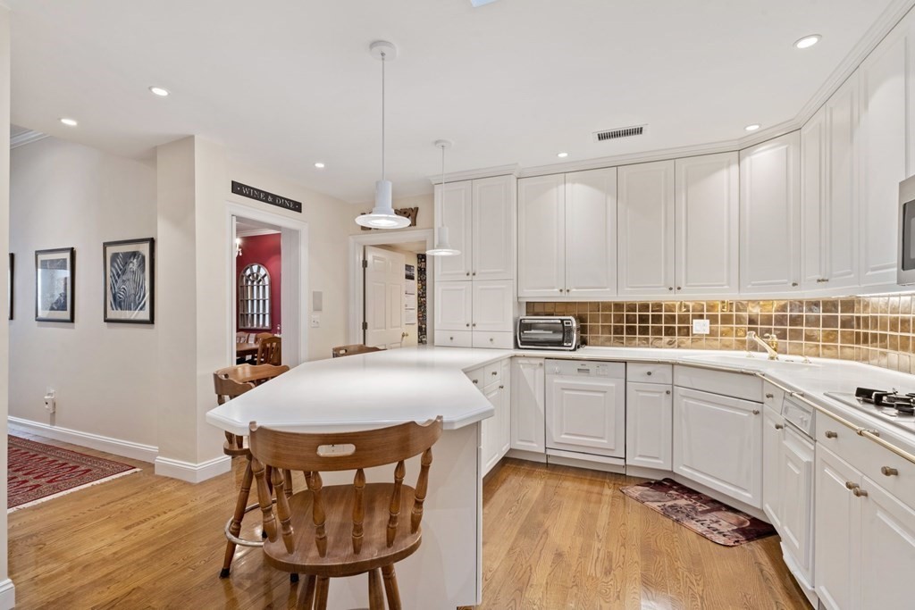 49 Rawson Road, Unit 49 Brookline, MA 02445 - Photo 10 of 42 a kitchen with stainless steel appliances granite countertop a dining table chairs and white cabinets