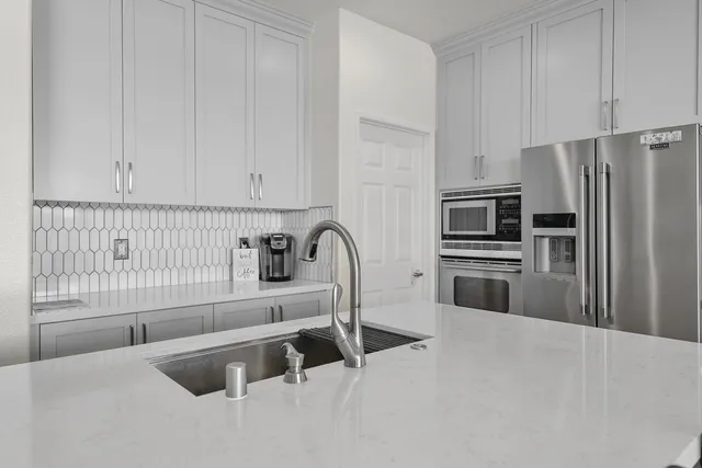 a kitchen with granite countertop a refrigerator sink and white cabinets