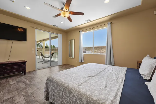 a spacious bedroom with a bed and a flat screen tv