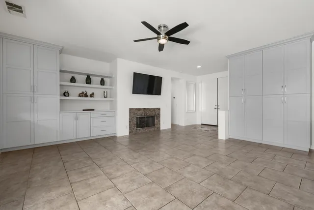 an empty room with fireplace ceiling fan and windows
