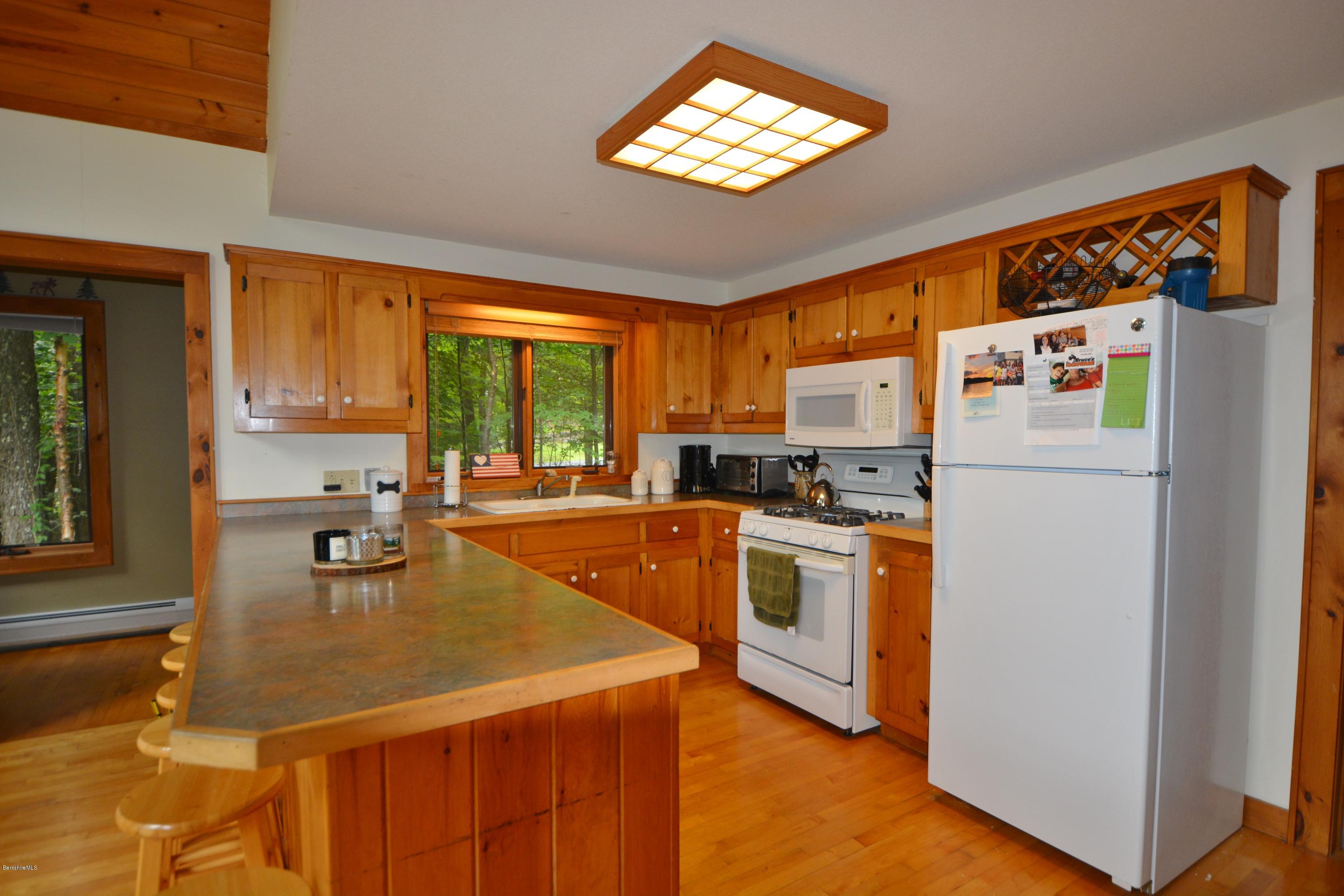 70 Rainbow Road Otis, MA 01029 - Photo 6 of 18 a kitchen with a refrigerator a stove a sink and dishwasher with wooden floor