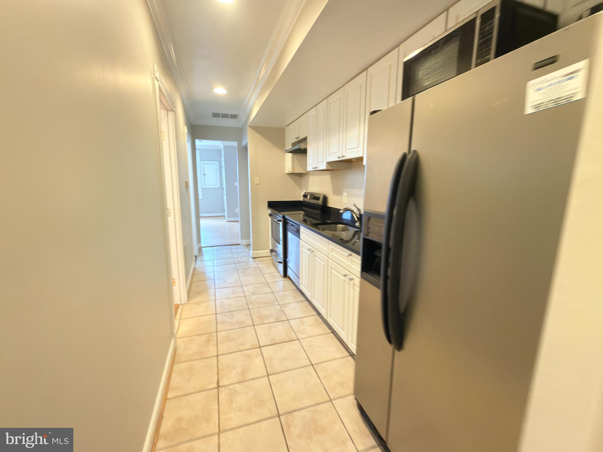 1246 Queen Street Northeast, Unit 2 Washington, DC 20002 - Photo 7 of 23 a kitchen with stainless steel appliances a refrigerator a sink a stove a microwave and cabinets