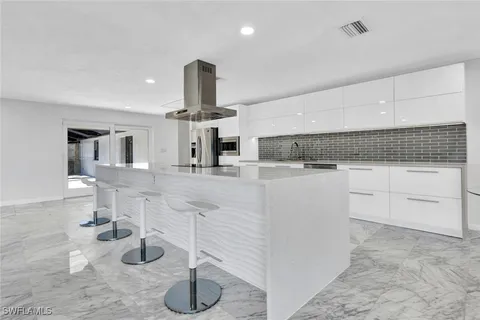 a kitchen with stainless steel appliances kitchen island granite countertop a refrigerator a stove and a sink