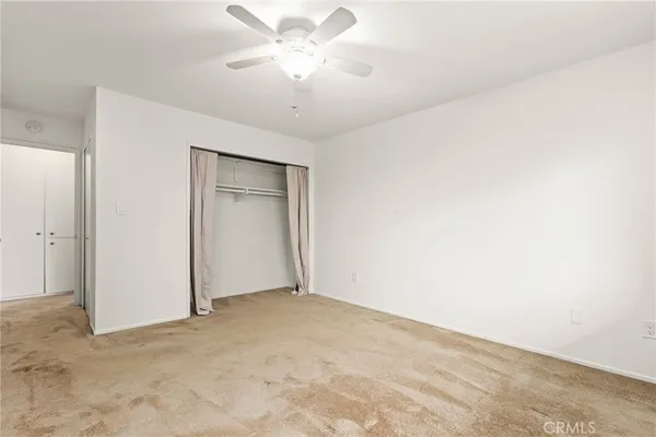 an empty room with a chandelier fan and windows