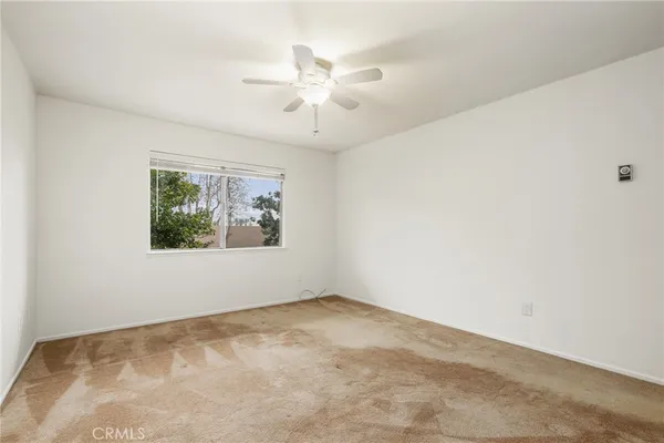 an empty room with windows and fan