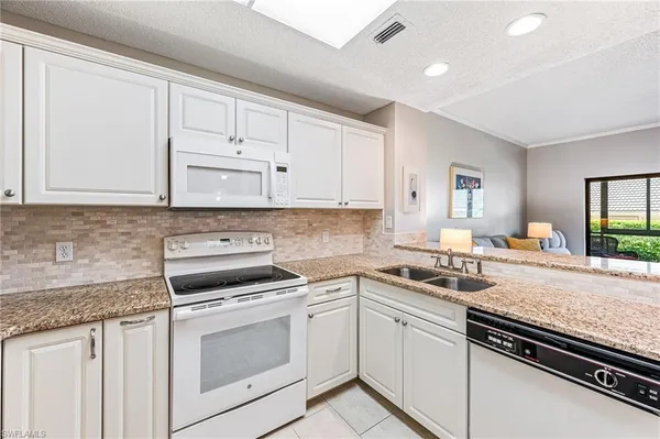 a kitchen with granite countertop white cabinets and appliances