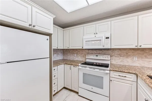 a white refrigerator freezer and cabinets in a kitchen