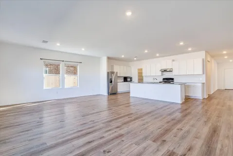 a view of kitchen with kitchen island wooden floors wooden cabinets and appliances