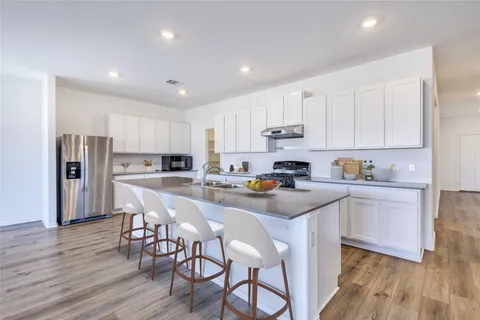 a kitchen with stainless steel appliances a table chairs refrigerator sink and microwave