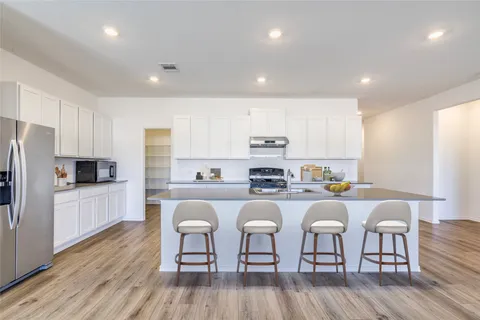 a kitchen with stainless steel appliances a microwave a stove a sink a refrigerator and cabinets