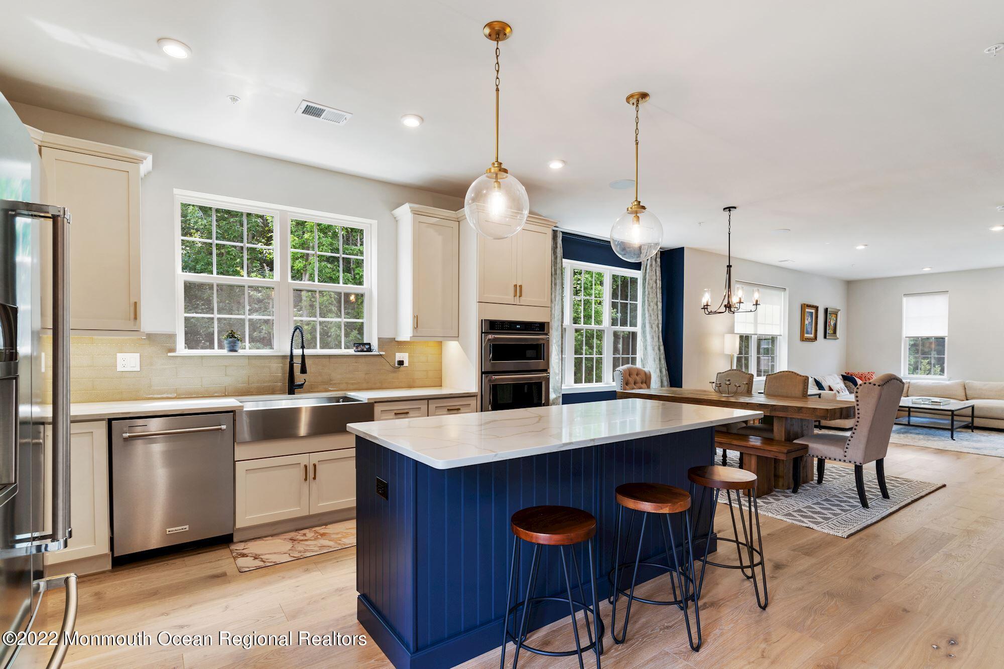 a open kitchen with stainless steel appliances granite countertop a stove top oven a sink dishwasher a dining table and chairs with wooden floor