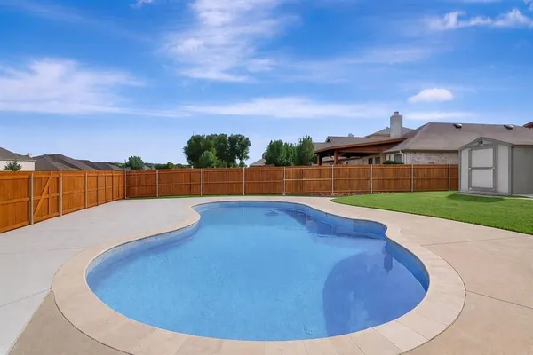 a view of swimming pool with outdoor seating and house in the background