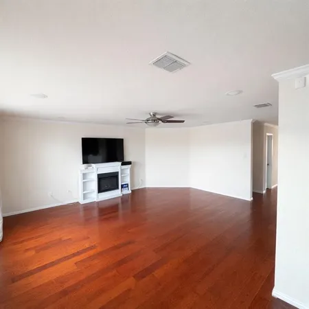 a view of an empty room with a kitchen and wooden floor