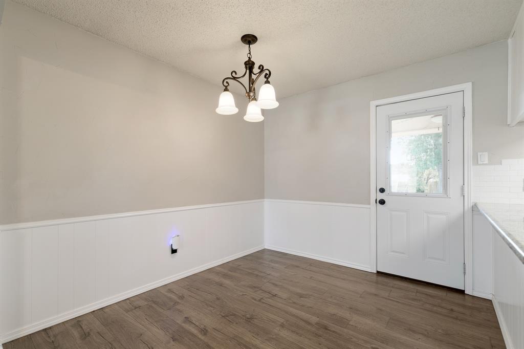 6612 Patsy Lane Watauga, TX 76148 - Photo 9 of 32 Dining area featuring wood-finish flooring, wainscoting, and a decorative chandelier