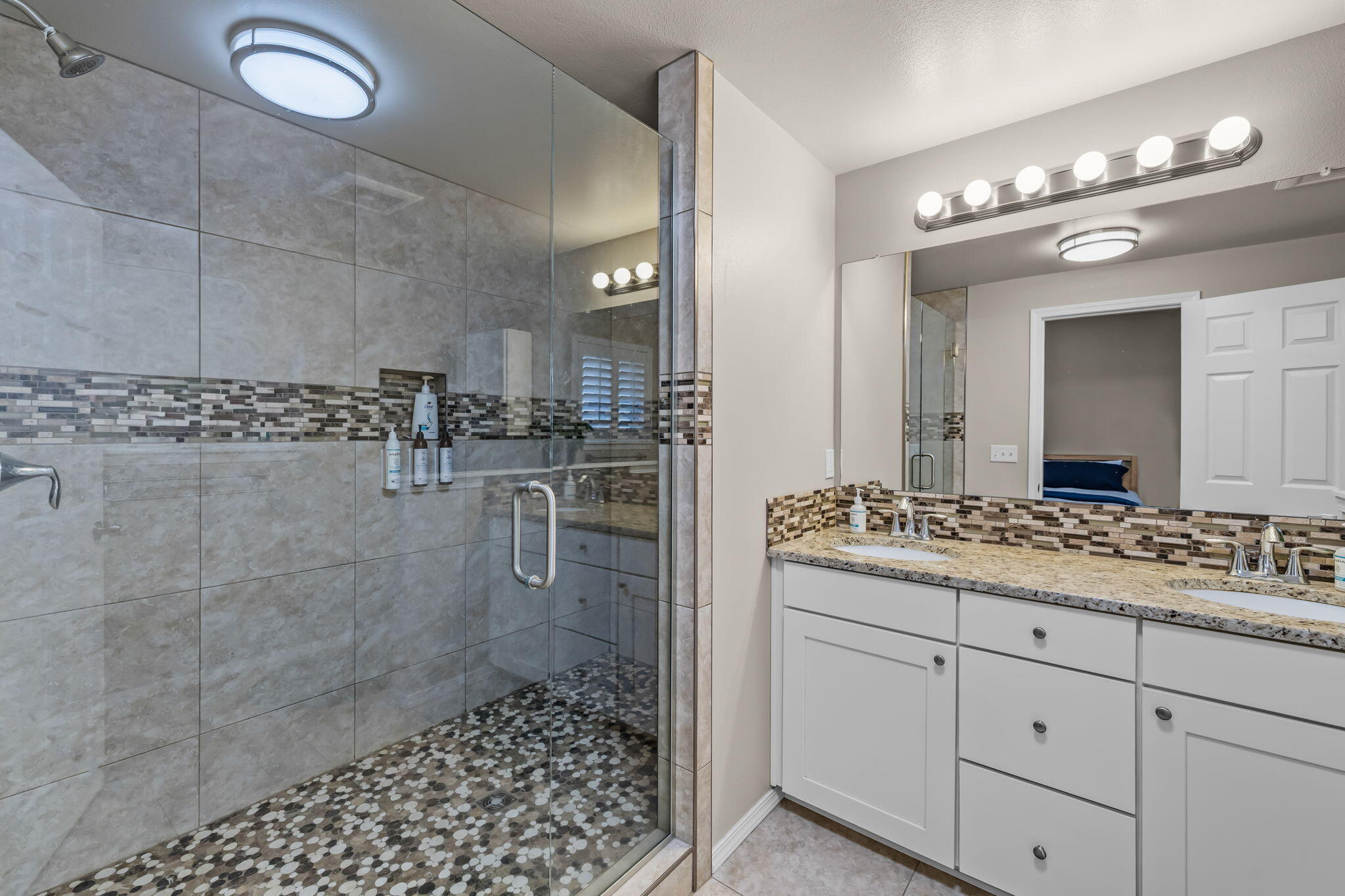 17064 Sacramento Road Bend, OR 97707 - Photo 18 of 50 a bathroom with a granite countertop sink a mirror and a shower