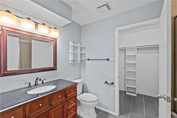 a bathroom with a granite countertop toilet sink and mirror