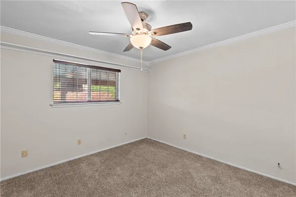 an empty room with ceiling fan and window