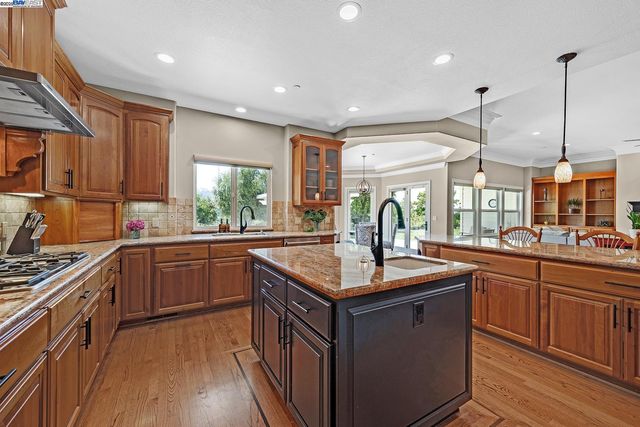 a kitchen with stainless steel appliances granite countertop a kitchen island a stove a sink a dining table and chairs
