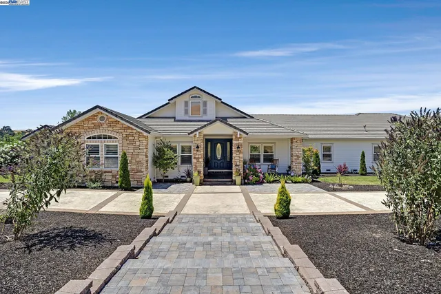 a front view of a house with a yard and potted plants