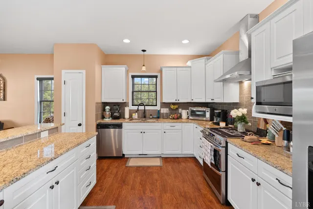 a large kitchen with stainless steel appliances kitchen island granite countertop a sink a stove and cabinets