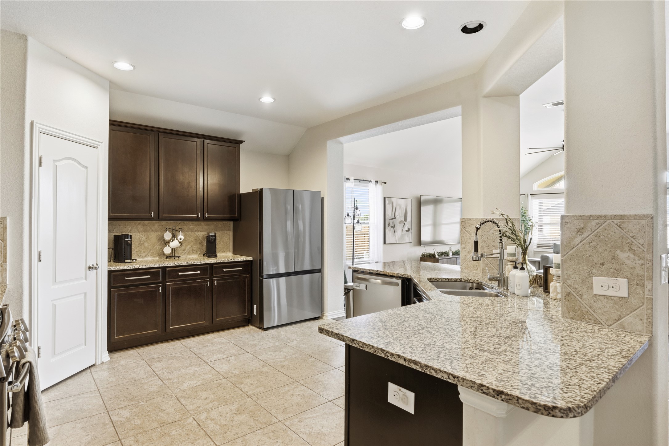 486 Pond View Pass Buda, TX 78610 - Photo 6 of 39 Modern kitchen featuring dark wood cabinetry, granite countertops, tile flooring, stainless steel appliances, and recessed lighting