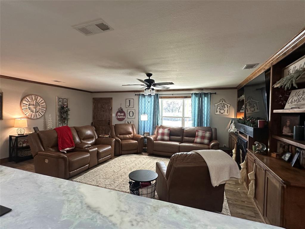 101 Twin Creek Road Comanche, TX 76442 - Photo 11 of 28 Living area featuring ornamental molding, ceiling fan, and wood finished floors