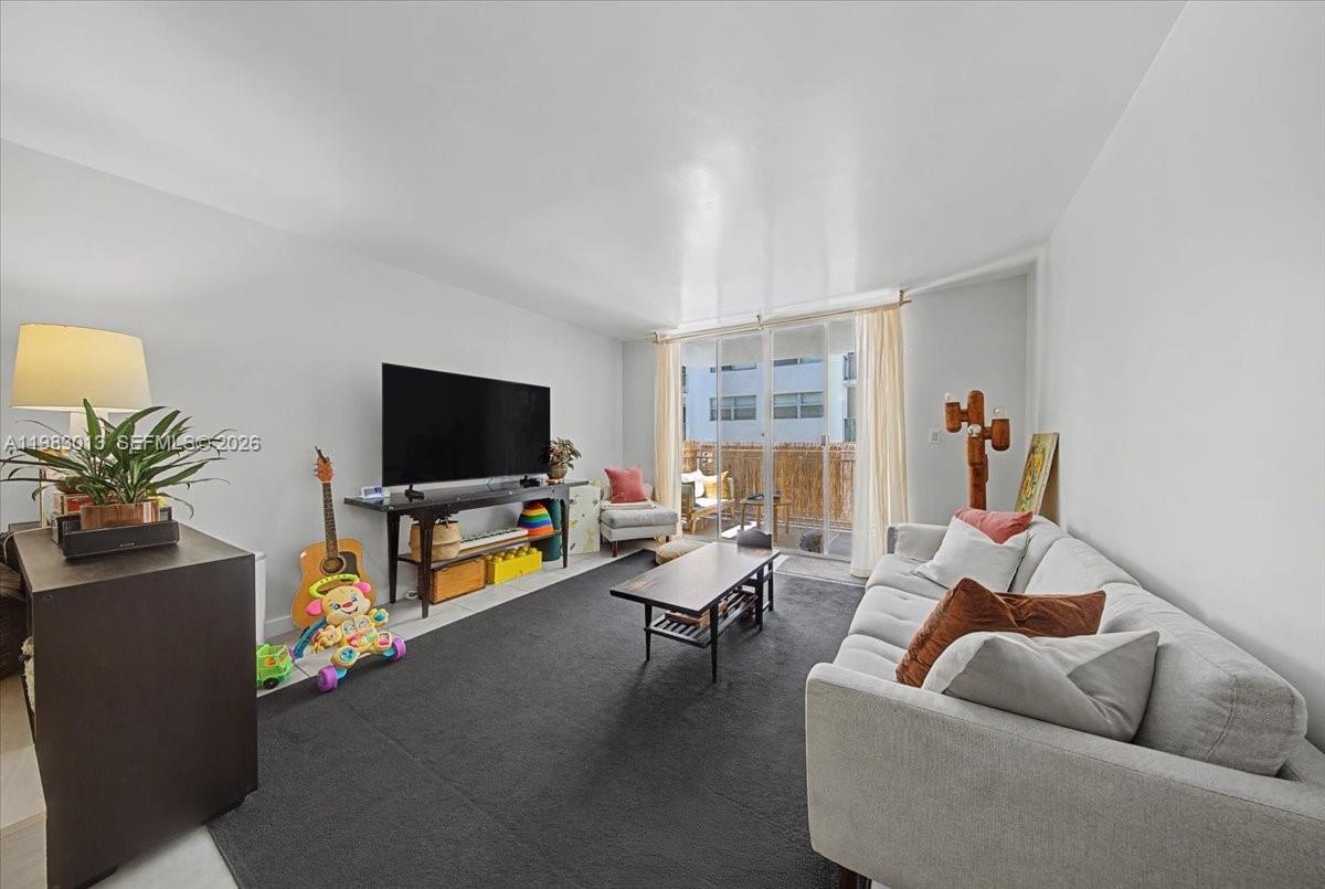 777 Northeast 62nd Street, Unit C211 Miami, FL 33138 - Photo 5 of 22 a living room with furniture and a flat screen tv