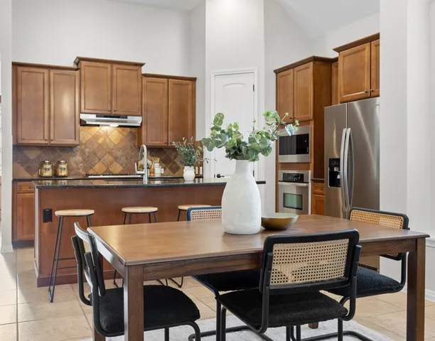 a kitchen with a table chairs refrigerator and microwave