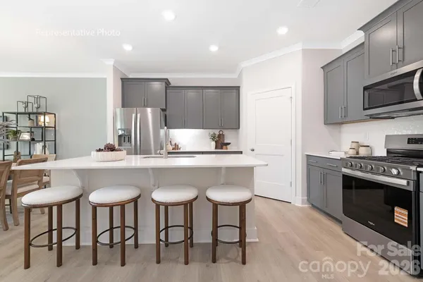 a kitchen with stainless steel appliances a table chairs refrigerator and microwave