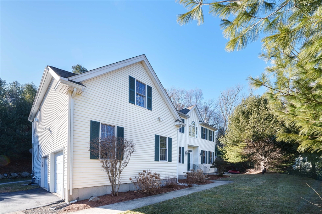 300 Crownshield Avenue Uxbridge, MA 01569 - Photo 2 of 24 a view of a white house next to a yard with plants and large trees