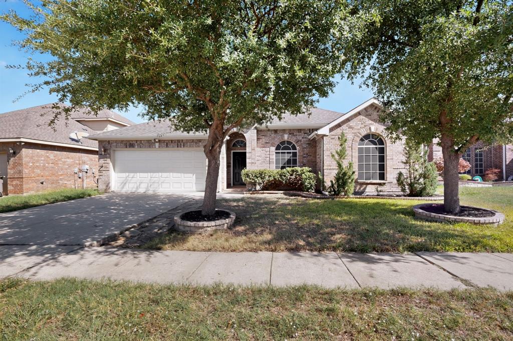 14908 Riverside Drive Little Elm, TX 75068 - Photo 5 of 40 Brick veneer exterior with arched windows, an attached two-car garage, and mature trees