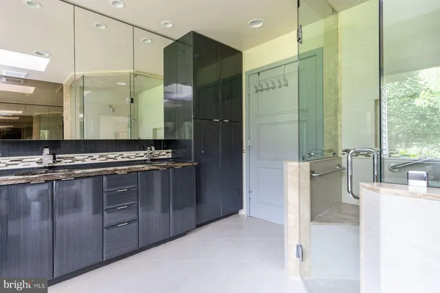 a bathroom with a granite countertop sink a large mirror and a shower