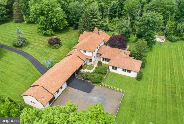 an aerial view of a house with swimming pool garden and trees