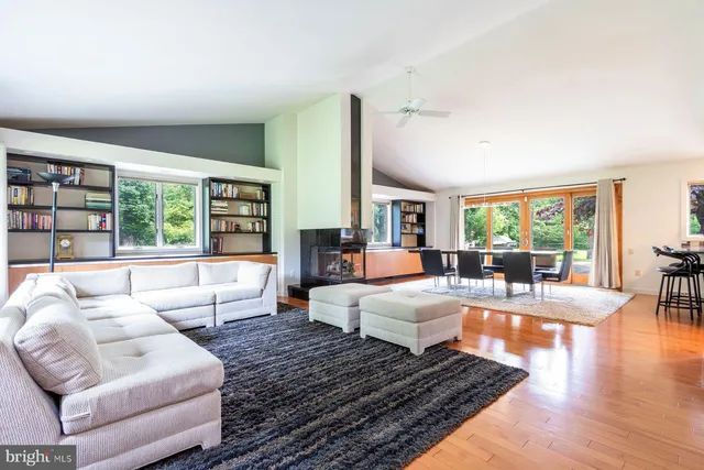 a living room with furniture large window and wooden floor