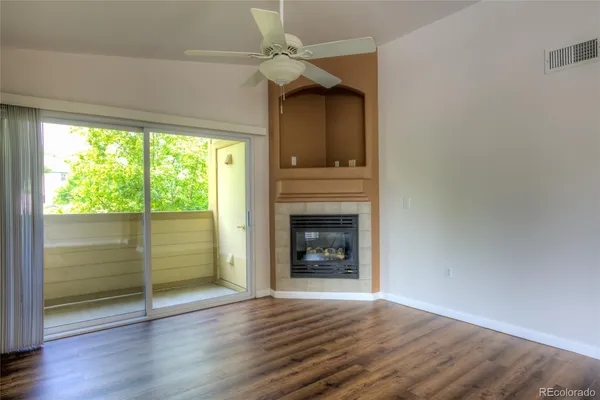 an empty room with wooden floor fireplace and windows