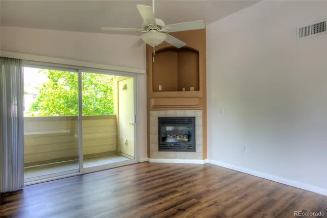an empty room with wooden floor fireplace and windows