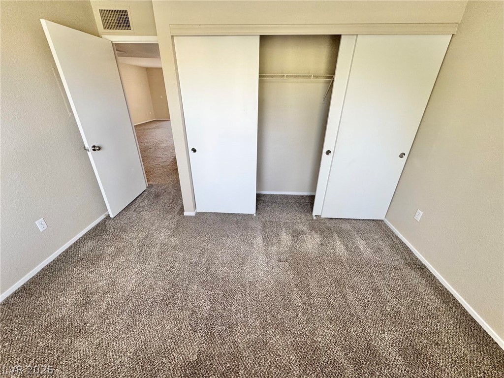 8070 West Russell Road, Unit 2121 Las Vegas, NV 89113 - Photo 8 of 22 Well-maintained carpeted bedroom with convenient sliding closet doors for ample storage.
