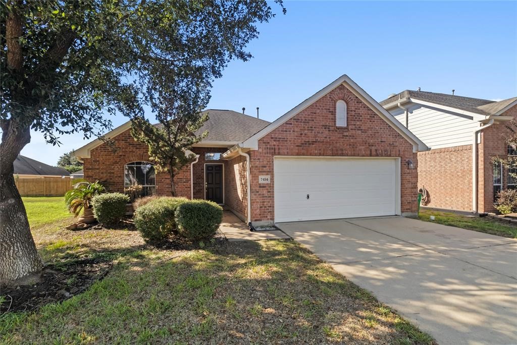 This is a charming single-story brick home with a two-car garage. The front yard features mature trees and well-maintained shrubs, providing a welcoming curb appeal. The driveway is spacious, and the exterior is in good condition, suggesting a well-kept property.