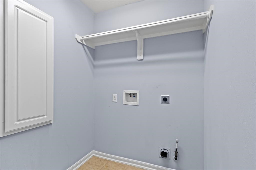 7454 Riven Oaks Court Cypress, TX 77433 - Photo 18 of 18 Laundry room with a light blue wall, a utility shelf, and hookups for a washer and dryer. There's also a wall cabinet for extra storage.