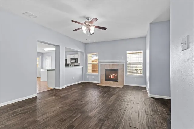 an empty room with wooden floor fireplace and windows